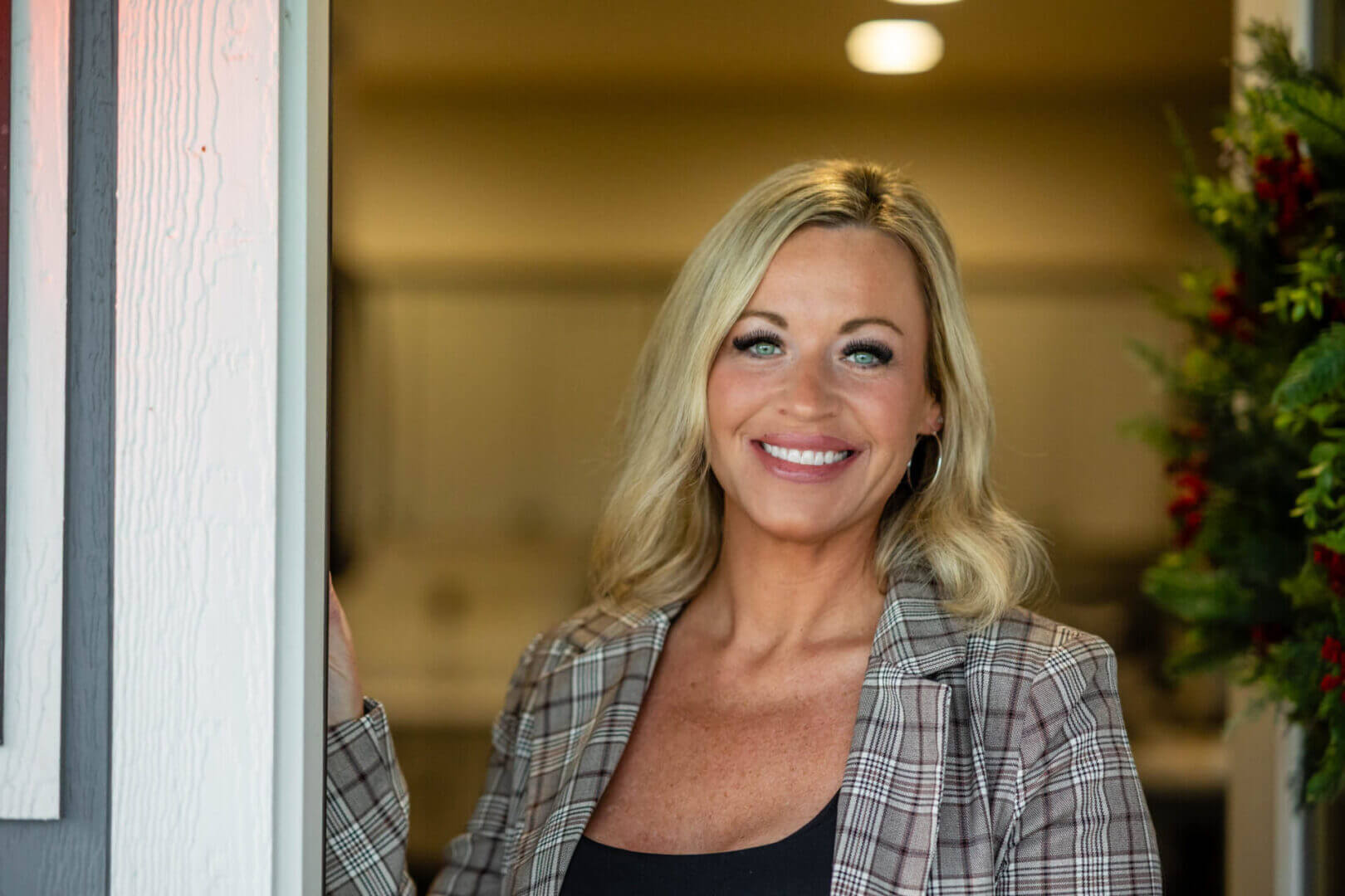 Smiling woman in plaid blazer at front door